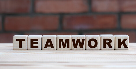 Obraz premium concept word TEAMWORK on cubes against the background of a brick wall