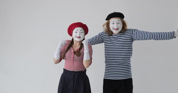 Excited mime artist couple celebrating success over white background