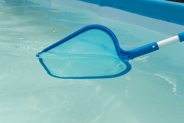 close up image of cleaning swimming pool with blue net. Maintenance and keeping pool clean from dirt and insects.