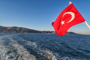 Turkish flag on the sea. View from the back of the boat, clear blue skies and blue sea. 