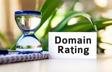 Domain rating business concept text on a white notebook and hourglass clock, green leaves of flowers