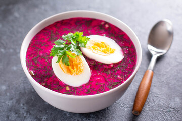 Cold borscht - speciality for hot summer days. Vegetable cold soup with beet, cucumber, radsih and egg on a concrete background