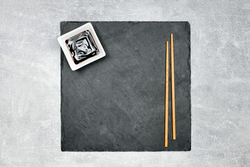 beautiful black granite sushi background board with chopsticks and teriyaki sauce