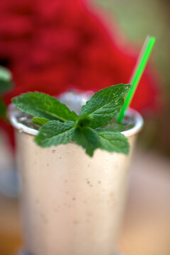 Mint julep drink in traditional silver cup, closeup, red roses in background