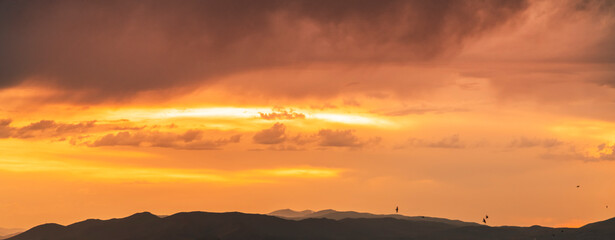 Beautiful bright sunset sky over the mountains silhouette . Dramatic orange clouds after sunset. Nature backgrounds. Golden sunset.