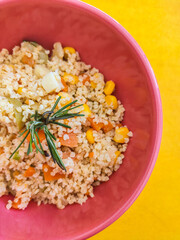 bowl of whole grain salad with yellow background with rosemary