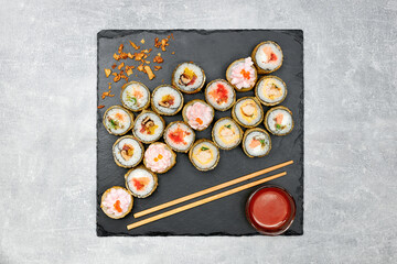 baked sushi set with side dishes on a black graphite board and gray background