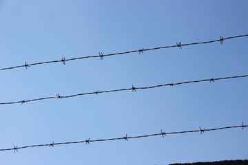 Barbed wires against clear blue sky. Prison and freedom concept crime and punishment law concept
