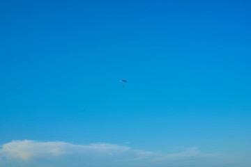 Hang glider with engine over blue sky