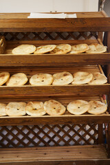 Round pita bread with a hole, flat unleavened white bread, tortilla baked in a tandoor. Ready fresh pita bread is on wooden shelves in the store