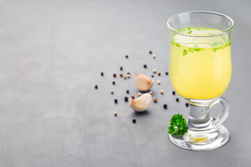 Chicken broth in a glass garnished with chopped parsley, horizontal, copy space
