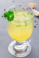 Chicken broth in glass garnished with chopped parsley, vertical, closeup