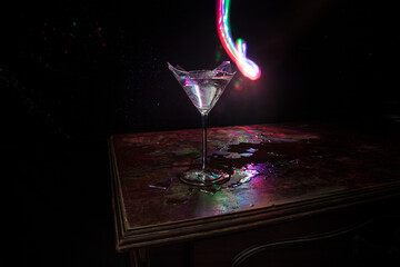 Broken glasses on wooden table at dark toned background with fog. Selective focus