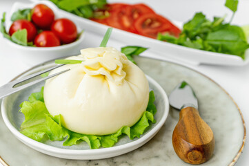 Burrata with Cutlery top view. dinner with tomato and spinach salad with Italian Buratto cheese. The concept of healthy Mediterranean food