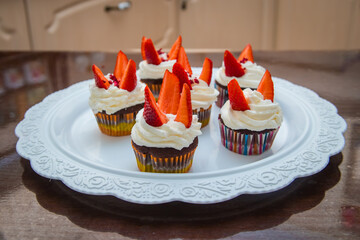 on the brown table are cupcakes decorated with strawberries