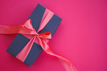 Girl holds a gift box and unties the bow. a girl opens a gift box. Gift box on a red background. Girl unties the tape from the box.
