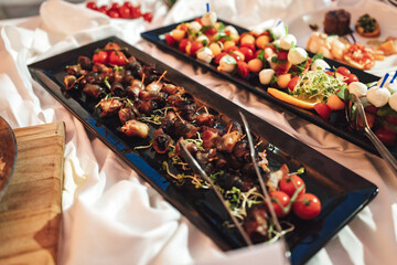 Self-service buffet table with various types of small snacks. Focused on bacon rolls. Celebration, party, birthday or wedding concept.