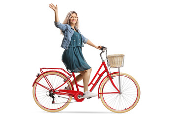 Fototapeta na wymiar Young woman riding a red bicycle and waving