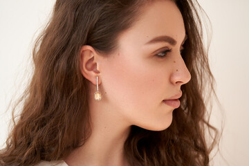 Fashionable portrait of a young beautiful girl with jewelry. Earrings with white crystals and diamonds.