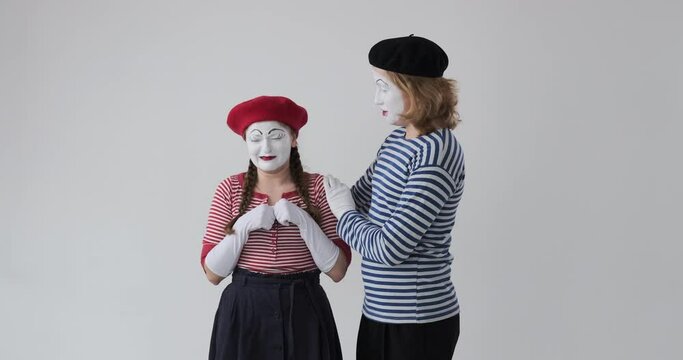Mime man consoling crying female mime artist over white background