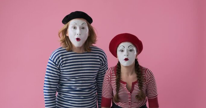Mime artist couple impressed on admiring something at far end over colored background