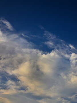portrait image of a white cloud, shaded with yellow and gray, blown by the winds under a blue sky. © conpuli