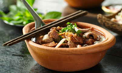 thai bowl of beef noodle soup in clay pot with duck liver