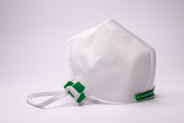 Covid-19 or coronavirus conceptual text on a white mouth and nose protection mask on light gray...