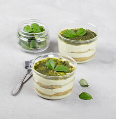 italian cream dessert tiramisu with green matcha tea in a glass Cup on a light background