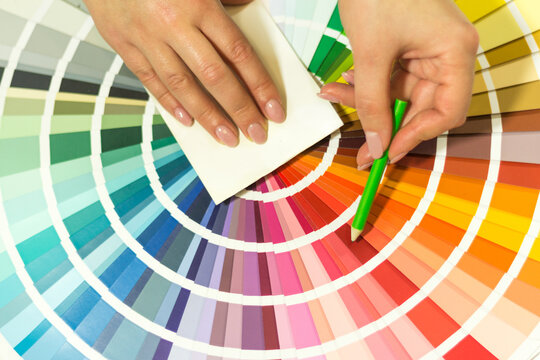 The hand of the designer shows a color palette. Catalog of rainbow color samples.
