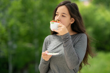 Girl holds a cup and inhales the aroma of strawberries. A white cup with strawberries