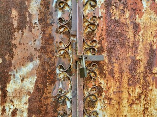 Rusted old metal door, hanging the key but not lock it. Weathered steel door.