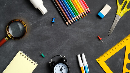 Frame of colorful school supplies on black board background. Top view, flat lay, overhead. Back to school concept.