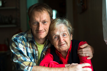 Portrait of a man embracing his old grandmother.
