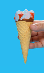 hand holding a  fresh marshmallow and raspberry flavor ice cream cone on blue background