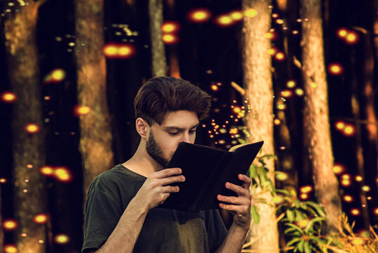 young man reading a book in florest at sunset