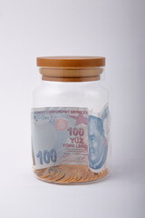 View of golden coins and banknotes, in jar on white background.