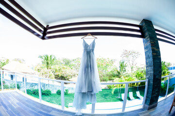 Obraz na płótnie Canvas Wedding gown dress hanging on before outdoor wedding of tropical caribbean destination marriage matrimonial ceremony on the white sandy beach in Dominican republic 