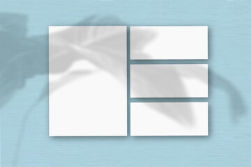 Several horizontal and vertical sheets of white textured paper on the background of a blue wall....