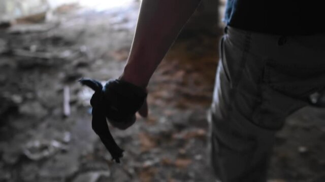 A man with a bandaged piece of cloth hand goes through the dark room of an abandoned house