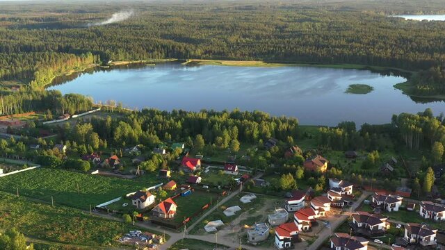 Village with summer houses in the forest with lake. Aerial view from copter