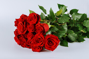 Bouquet of red roses with lush green leaves on a white background