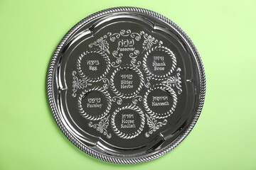 Passover Seder plate (keara) on light green background, top view. Pesah celebration