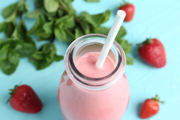 Tasty strawberry smoothie in bottle on table, closeup
