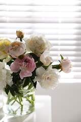 Obraz na płótnie Canvas Beautiful peonies in vase on table near window indoors