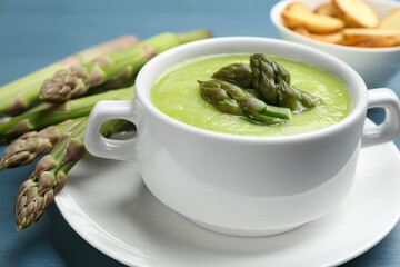 Delicious asparagus soup served on blue table,