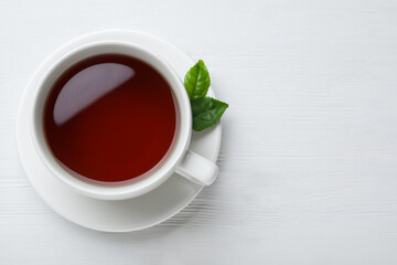 Cup of tasty black tea on white wooden table, top view. Space for text