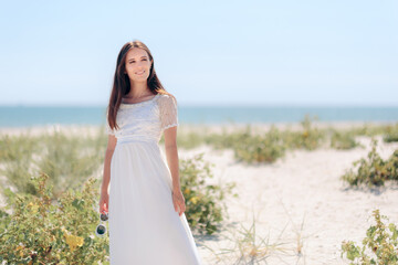 Fototapeta na wymiar Fashion Woman with Sunglasses Wearing Long White Dress to the Beach