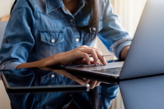 Young casual business woman work on laptop computer with digital tablet on the desk at home. Online learning, remote working or telework concept.