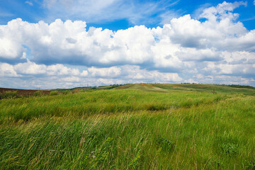 Summer natural landscape, meadow, field, hills. Beautiful blue sky with clouds.